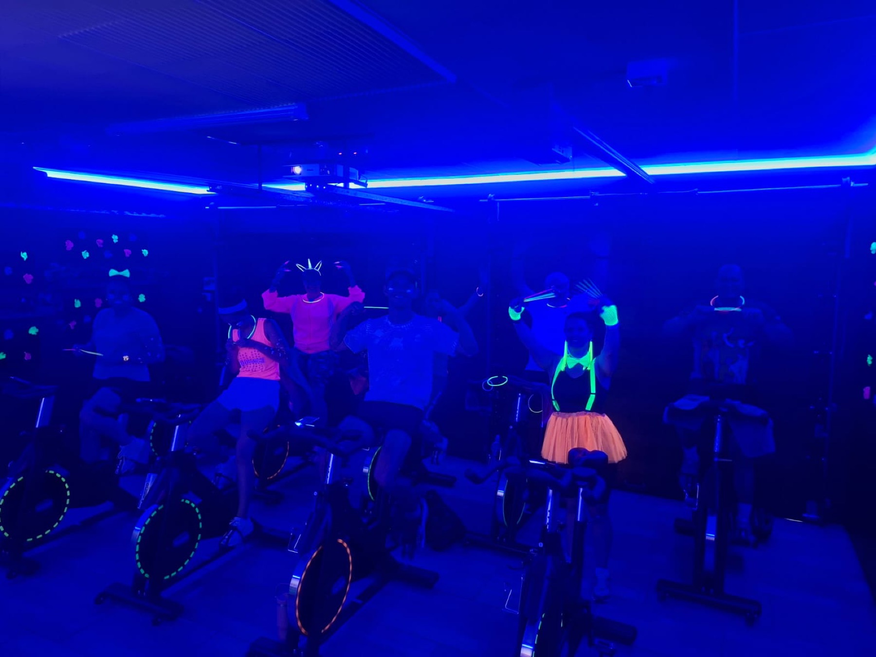 A SpinX indoor cycling class under vivid blue and neon lighting